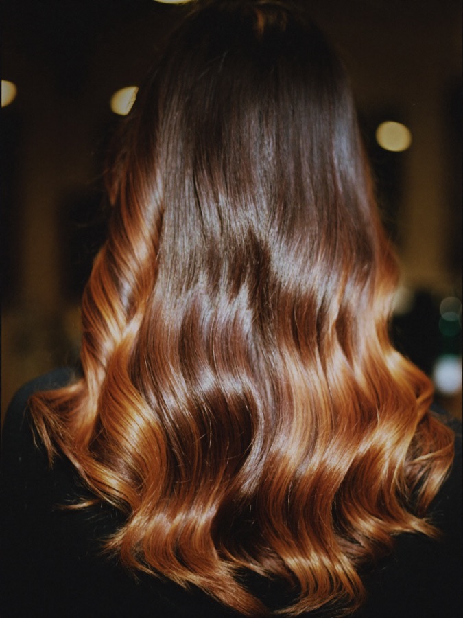 Finished balayage falling in glossy waves from dark roots to caramel ends.