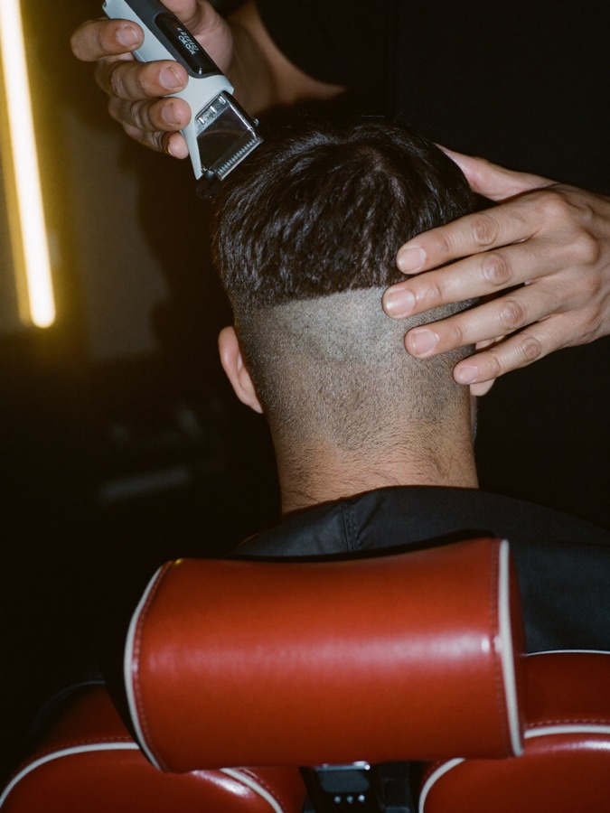 Clippers running up the back of a head, cutting a clean skin fade.
