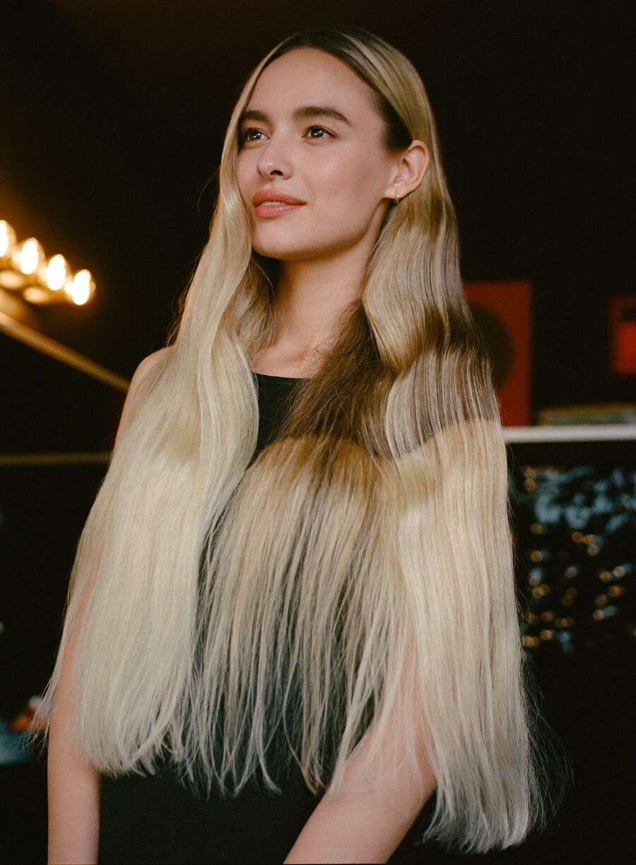 Gloved hands folding a foil into sectioned blonde highlights.